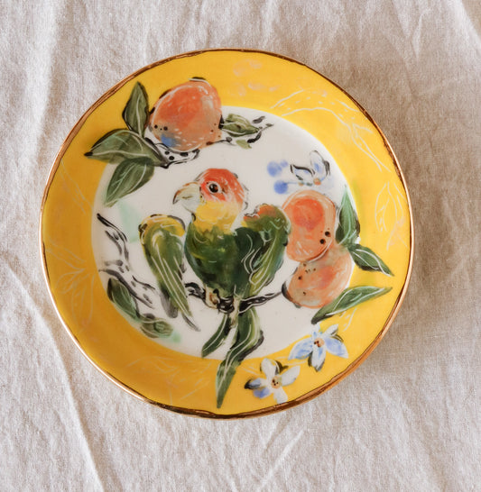 Carolina Parakeet Perched over Orange Branch Plate (left facing)